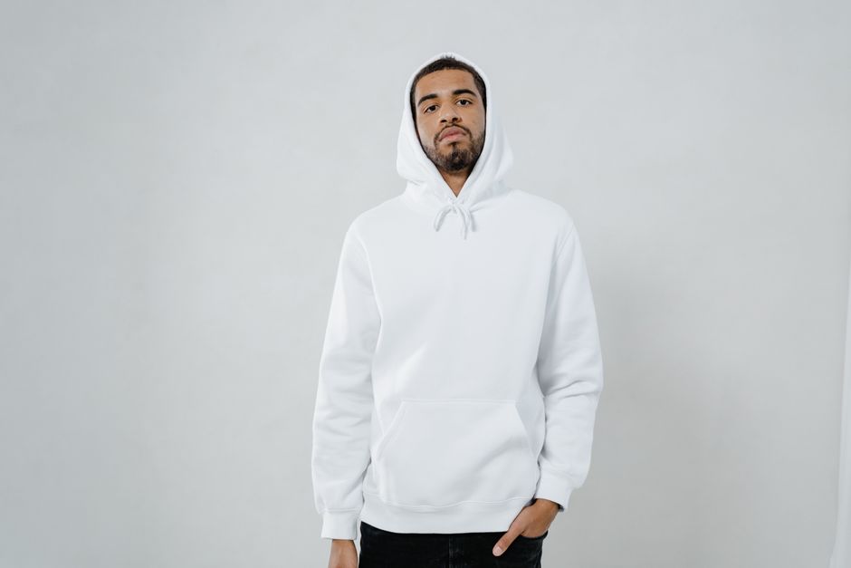Man in casual white hoodie standing against a neutral background, suitable for lifestyle imagery.