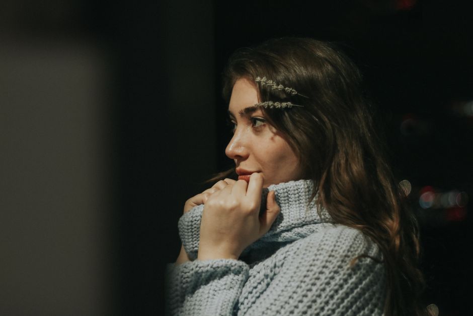 Side profile of a woman with wavy hair in a knitted sweater at night, exuding warmth and thoughtfulness.