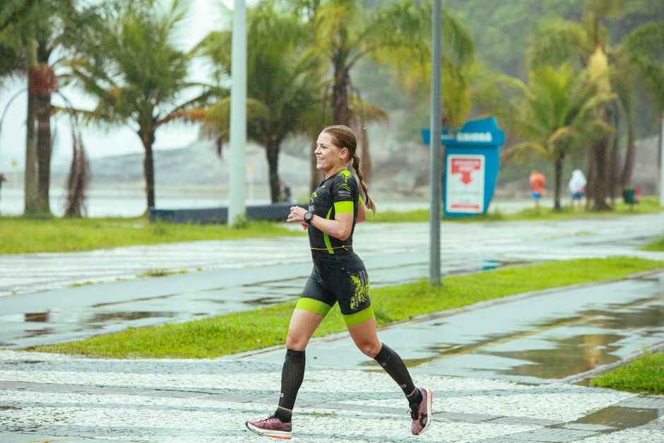 A woman running on a wet path surrounded by palm trees, showcasing fitness and determination.