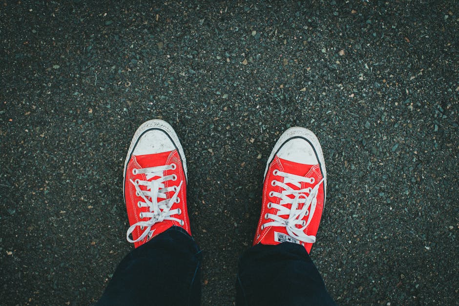 Close-up of red sneakers on asphalt, showcasing casual footwear style.