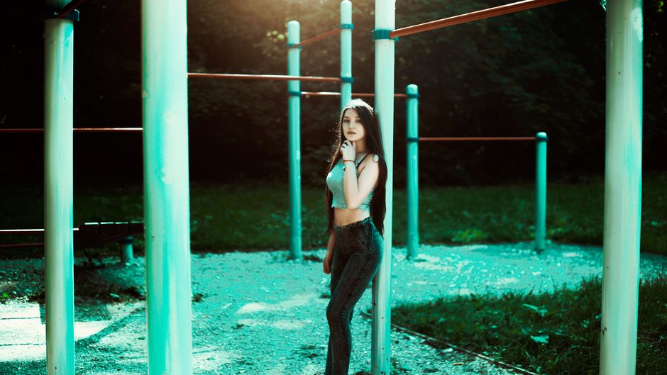 Fashionable woman posing at an outdoor gym with vibrant lighting. Perfect for lifestyle and fitness themes.