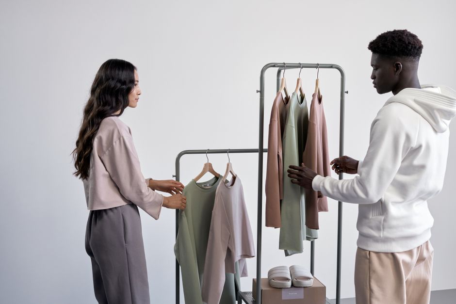 Two adults browsing trendy casual wear in a modern showroom with a pastel palette.
