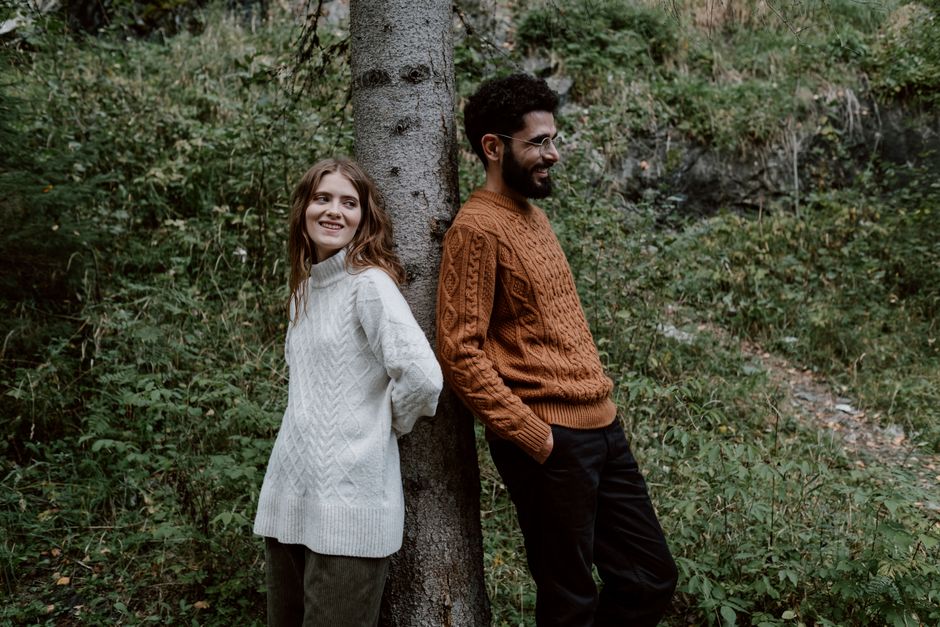 A happy couple leaning against a tree, enjoying the natural wilderness outdoors.
