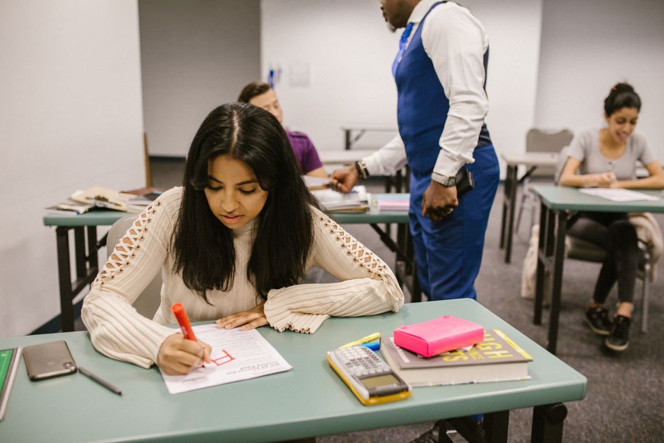 Students in a classroom during examination discussing and writing notes.