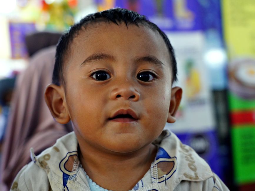 Adorable toddler with expressive eyes looking curiously at the camera indoors.