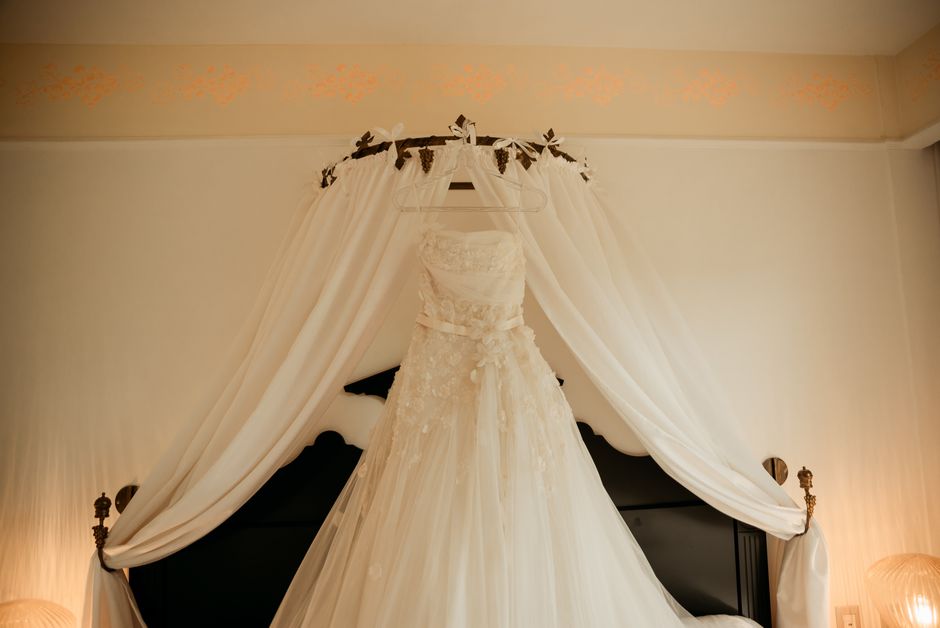 A luxurious wedding dress elegantly displayed on a bed canopy in a stylish bedroom setting.
