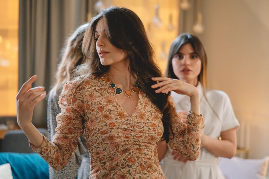 Elegant women dancing indoors, showcasing long hair and floral patterned dresses.