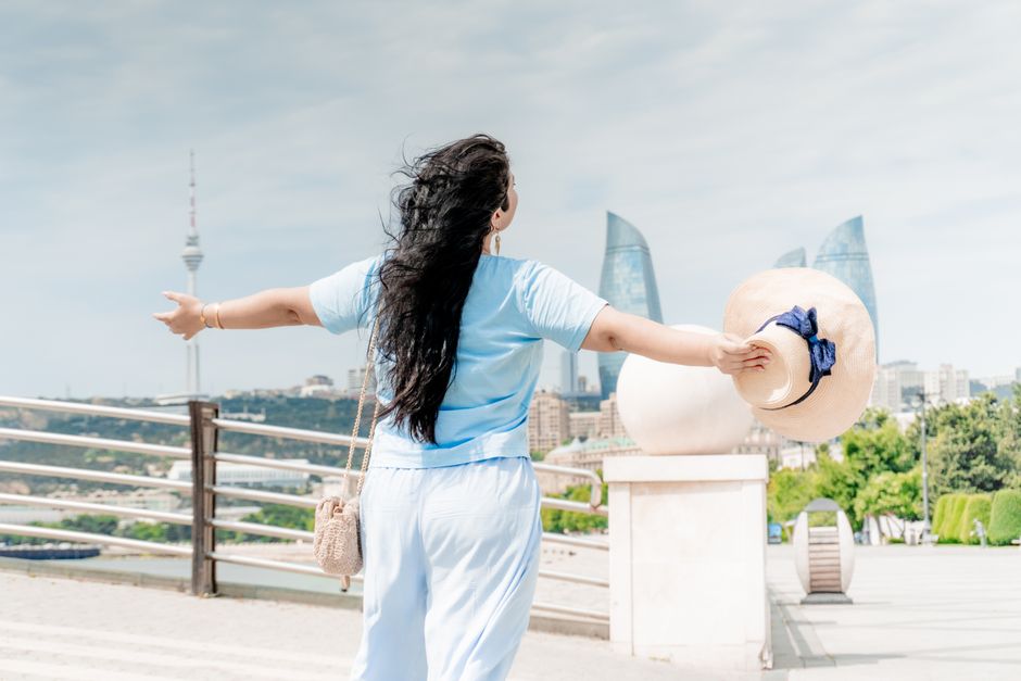 A woman standing outdoors in Baku, Azerbaijan, enjoying the skyline with the Flame Towers in view.
