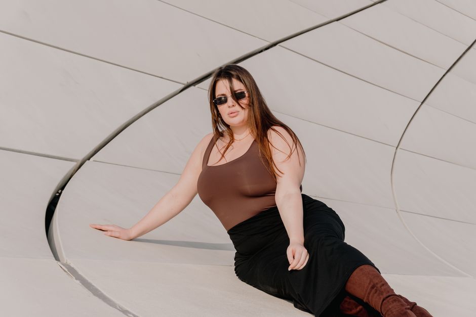Woman in fashionable attire posing by modern architecture outdoors.