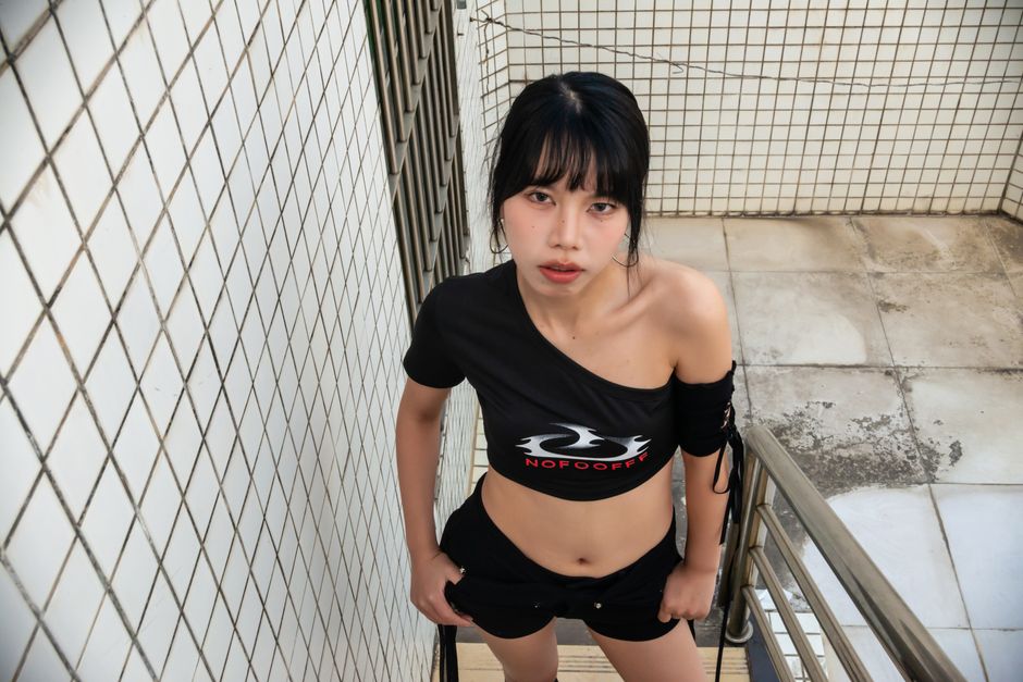 Young woman in stylish urban fashion poses outdoors on a staircase.