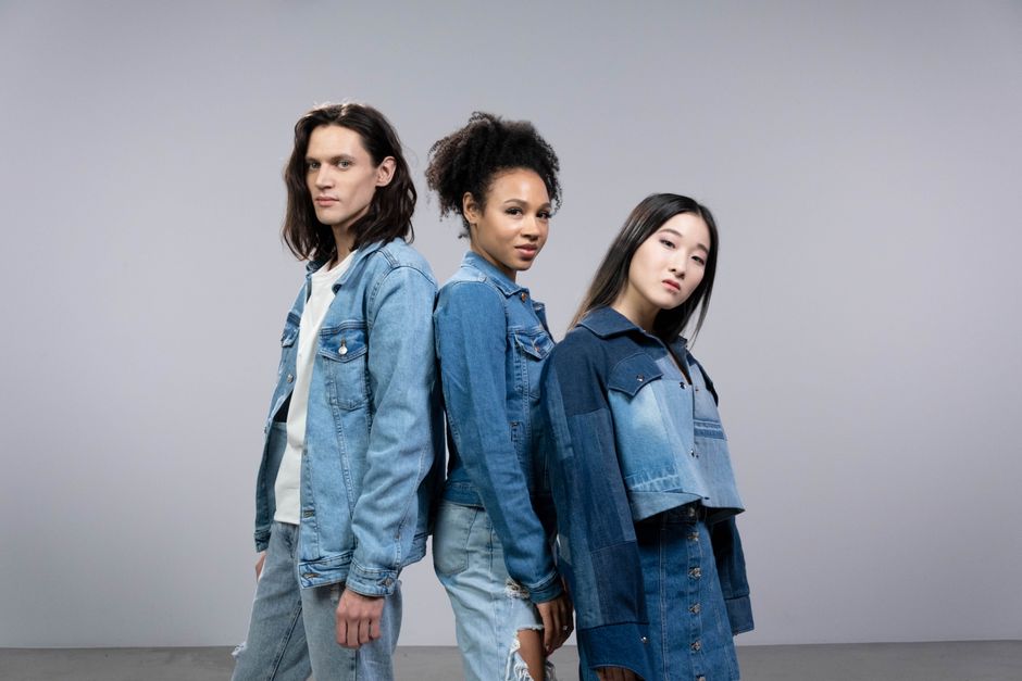 Three diverse models posing in stylish denim outfits in a studio setting.